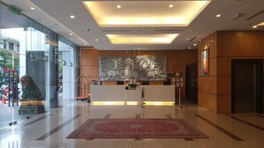 Un área de recepción de diseño moderno, con un mostrador de recepción, un mural grande en la pared y una alfombra roja.