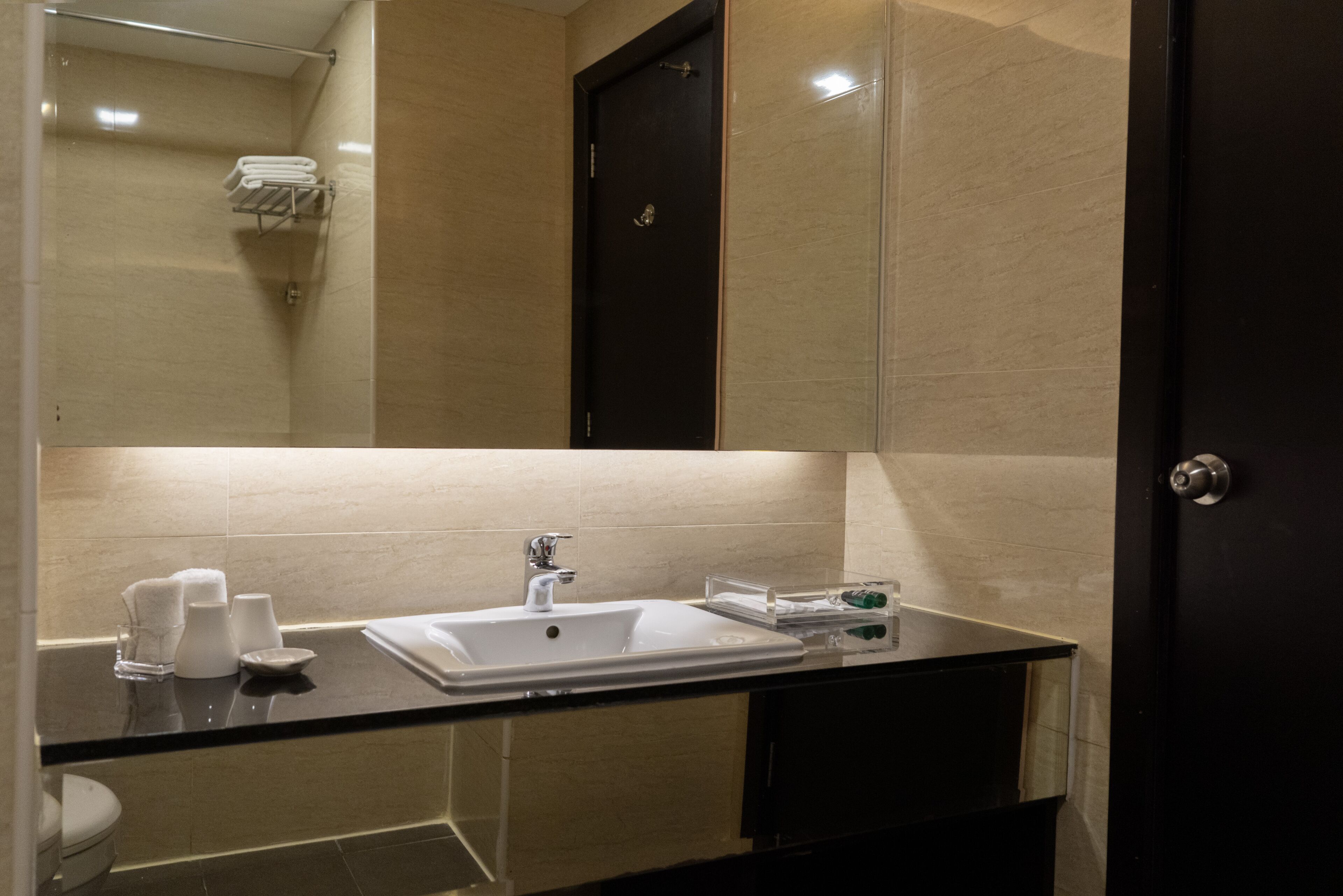A modern bathroom with a glass shower enclosure, a white sink with a mirror above, and a dark-toned vanity.