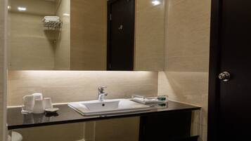A modern bathroom with a glass shower enclosure, a white sink with a mirror above, and a dark-toned vanity.