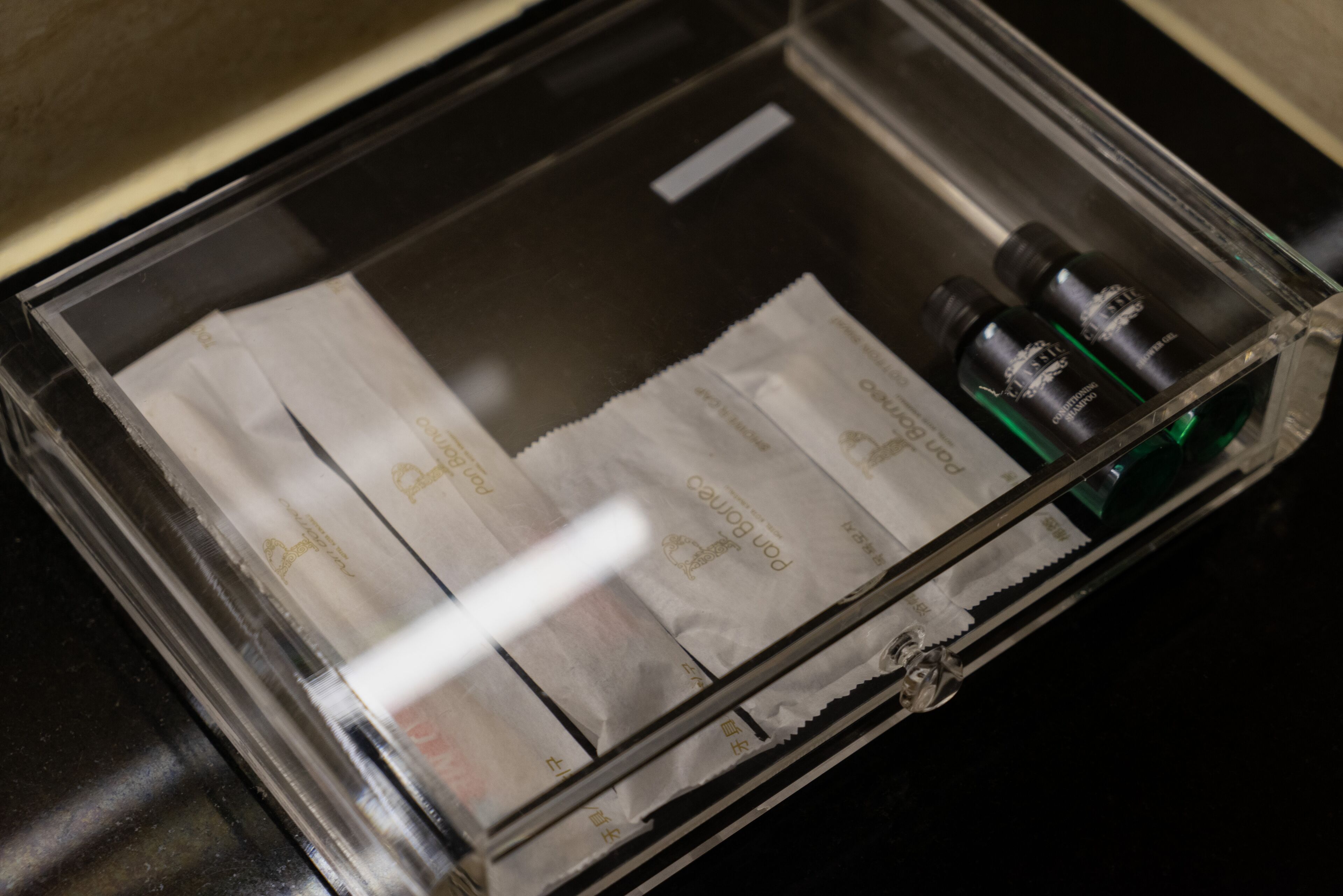 Un contenitore di plastica trasparente con diversi oggetti, tra cui due piccole bottiglie, un fazzoletto e della carta.