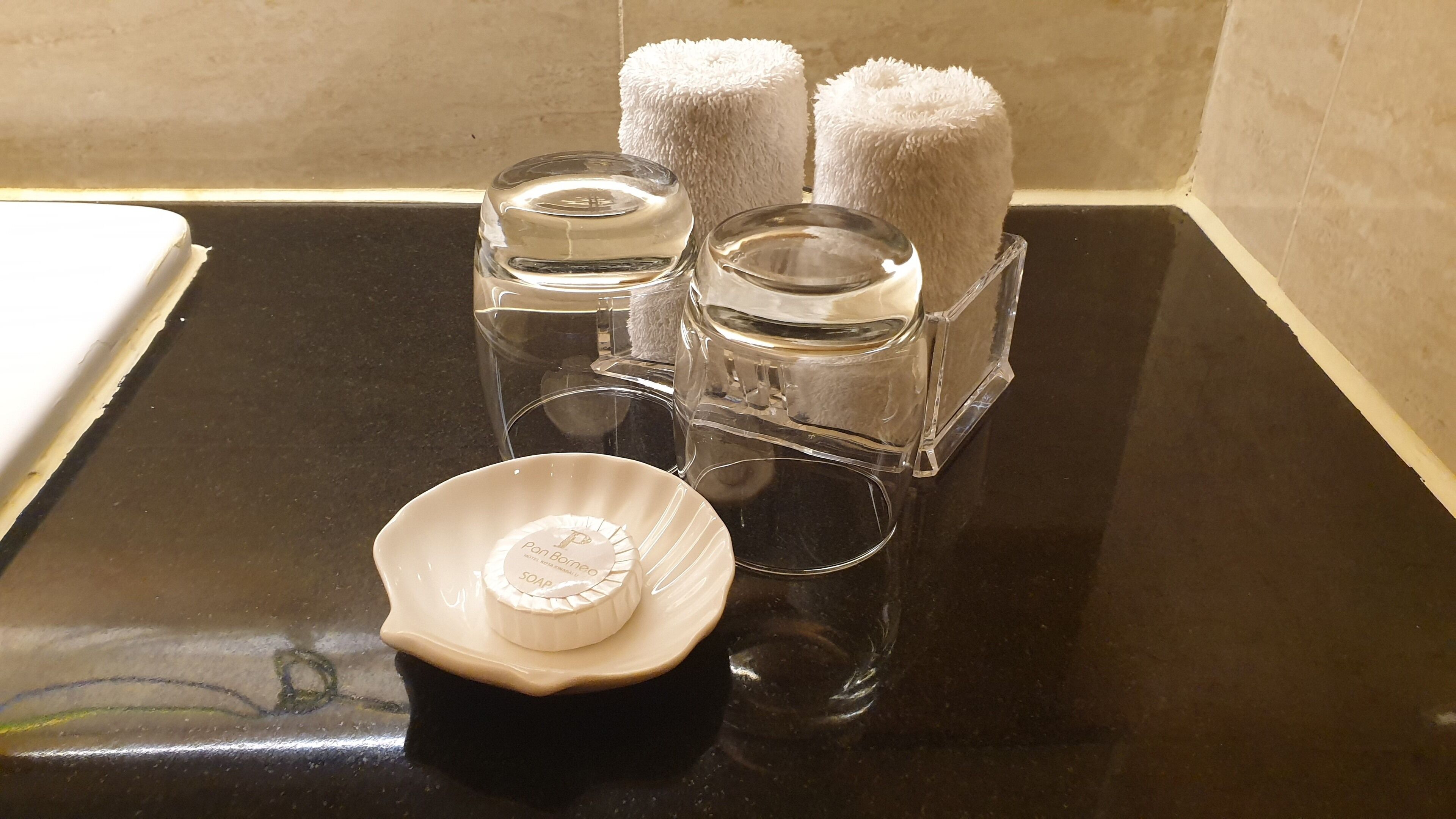 A bathroom counter with a soap dish, two glass containers, and two fluffy towels.