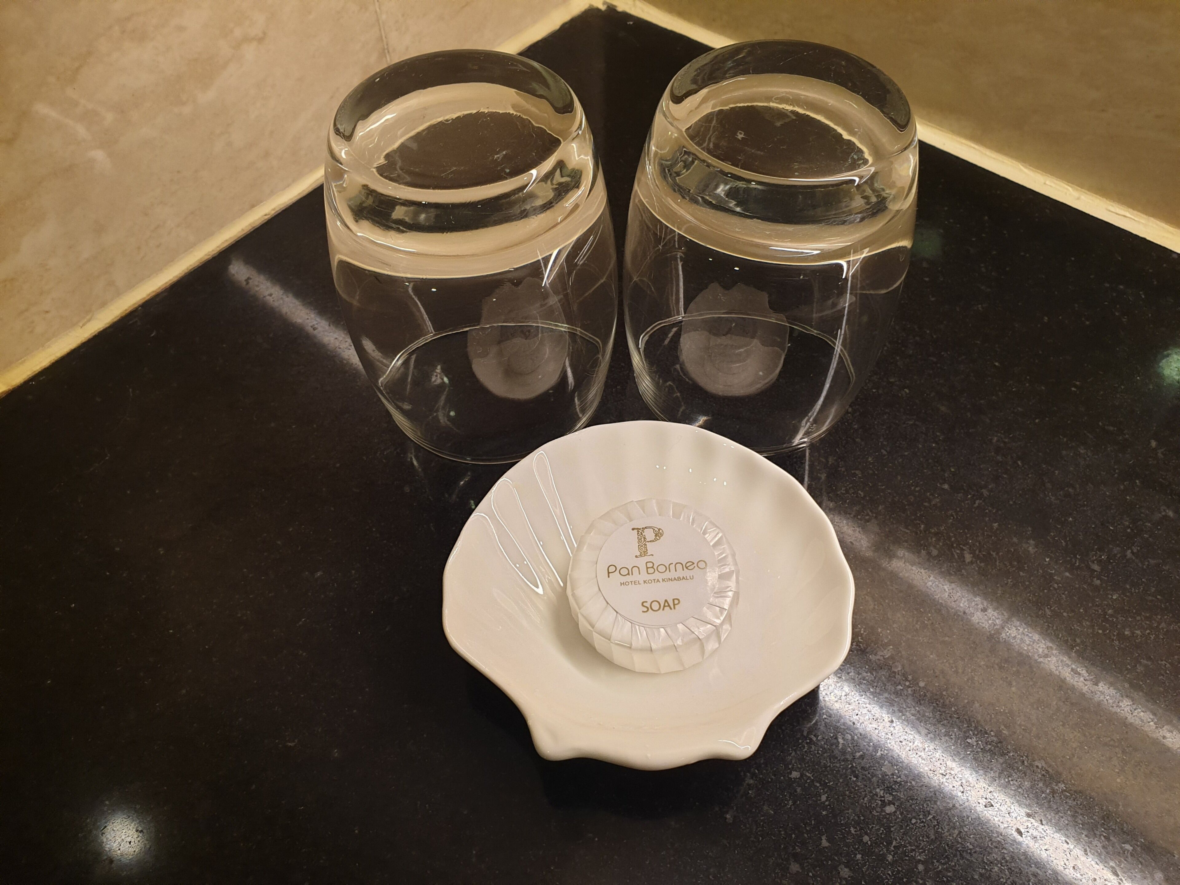 Two clear glass bottles and a white soap dish with a label on a black countertop.