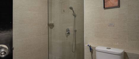 A glass-enclosed shower area with a toilet and a framed picture on the wall.