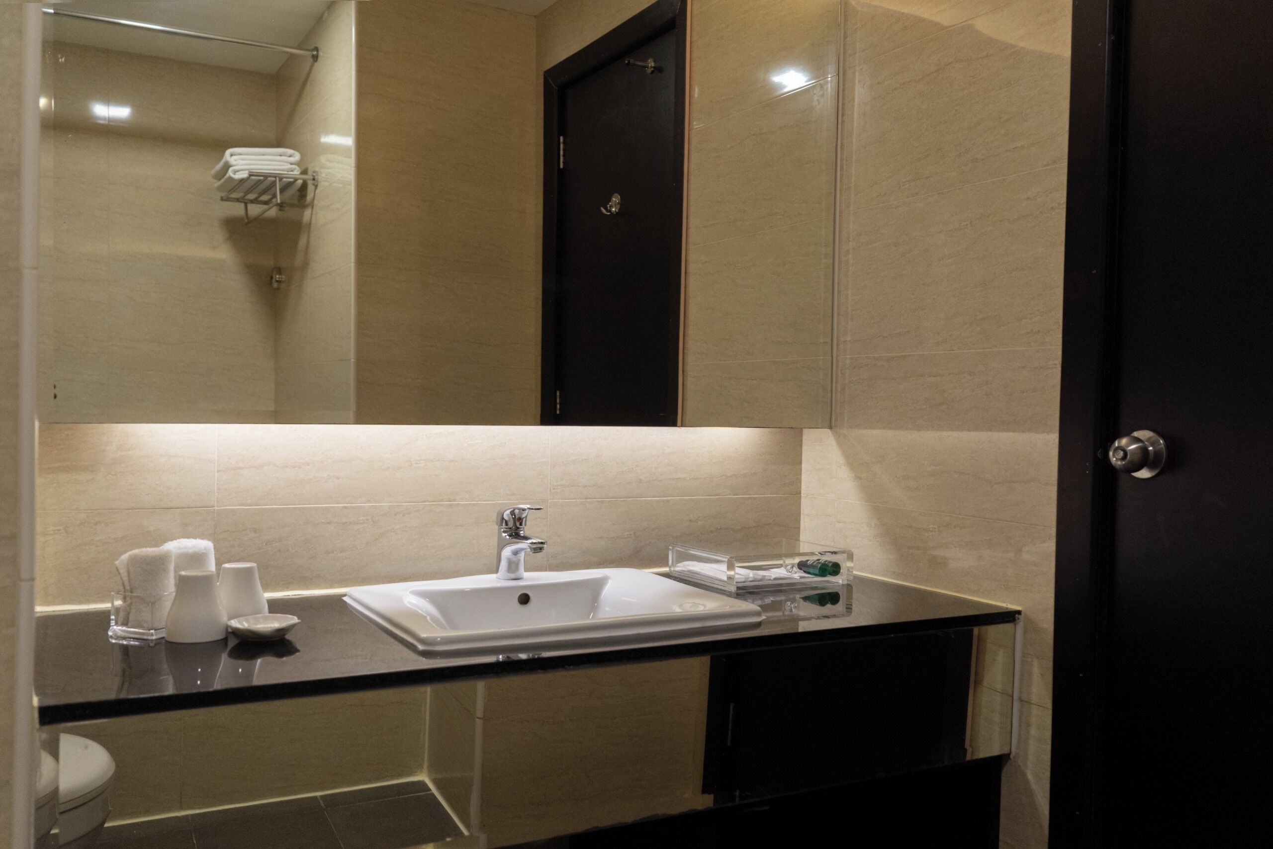 Une salle de bain moderne avec une douche à parois de verre, un lavabo blanc et un meuble sombre.