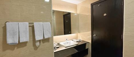 Un baño moderno con una puerta oscura, un lavamanos y un espejo.