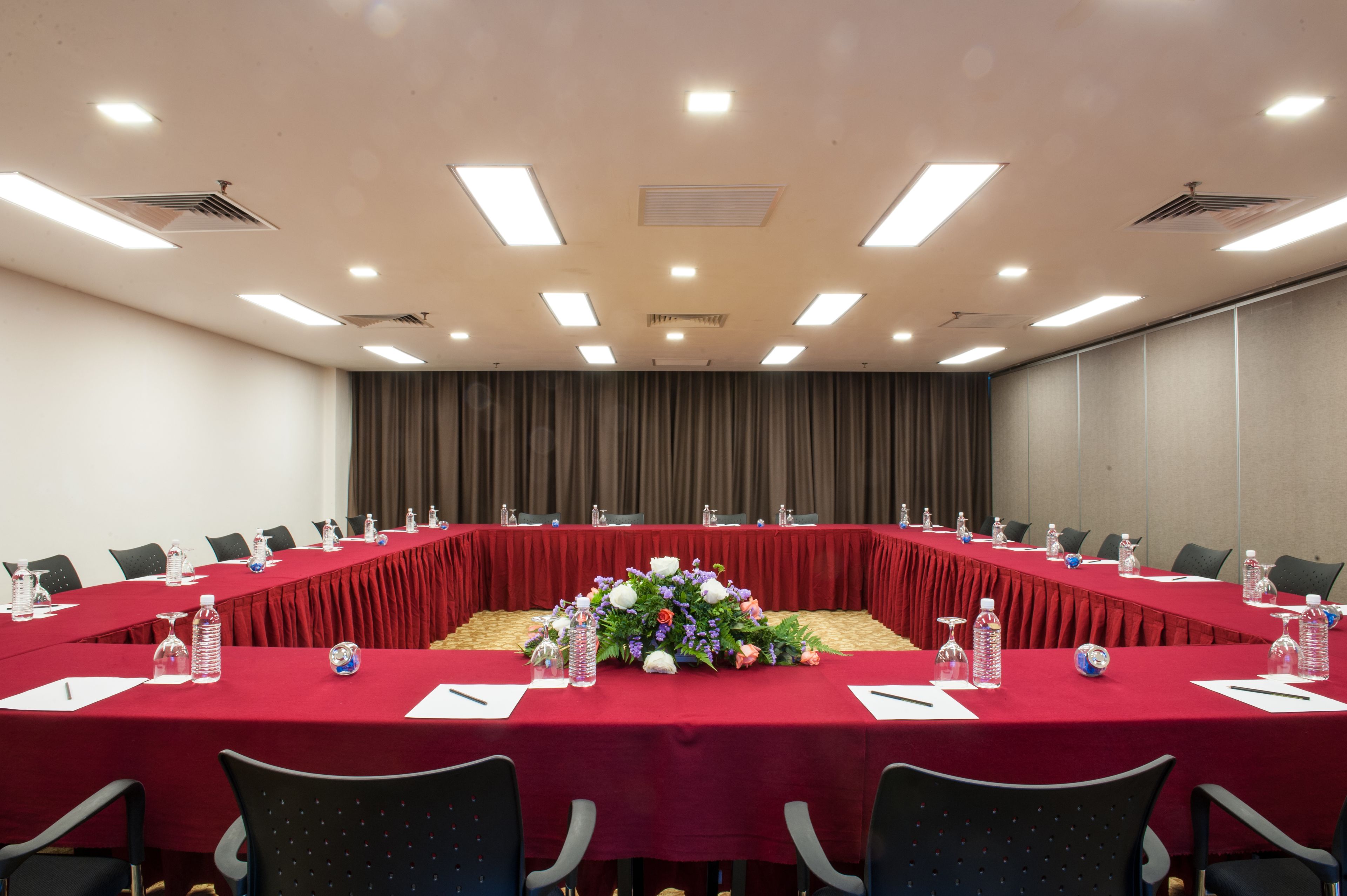 A conference room with a long table, red tablecloth, and floral centerpiece.
