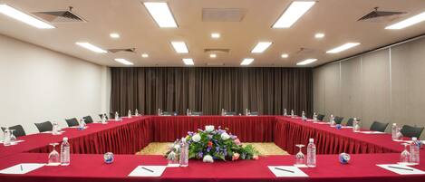 A conference room with a long table, red tablecloth, and floral centerpiece.