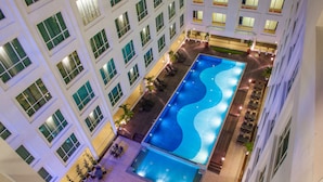 Ein mehrstöckiges Hotel mit einem großen Hallenbad, mehreren Balkonen und Außenbereichen zum Sitzen.