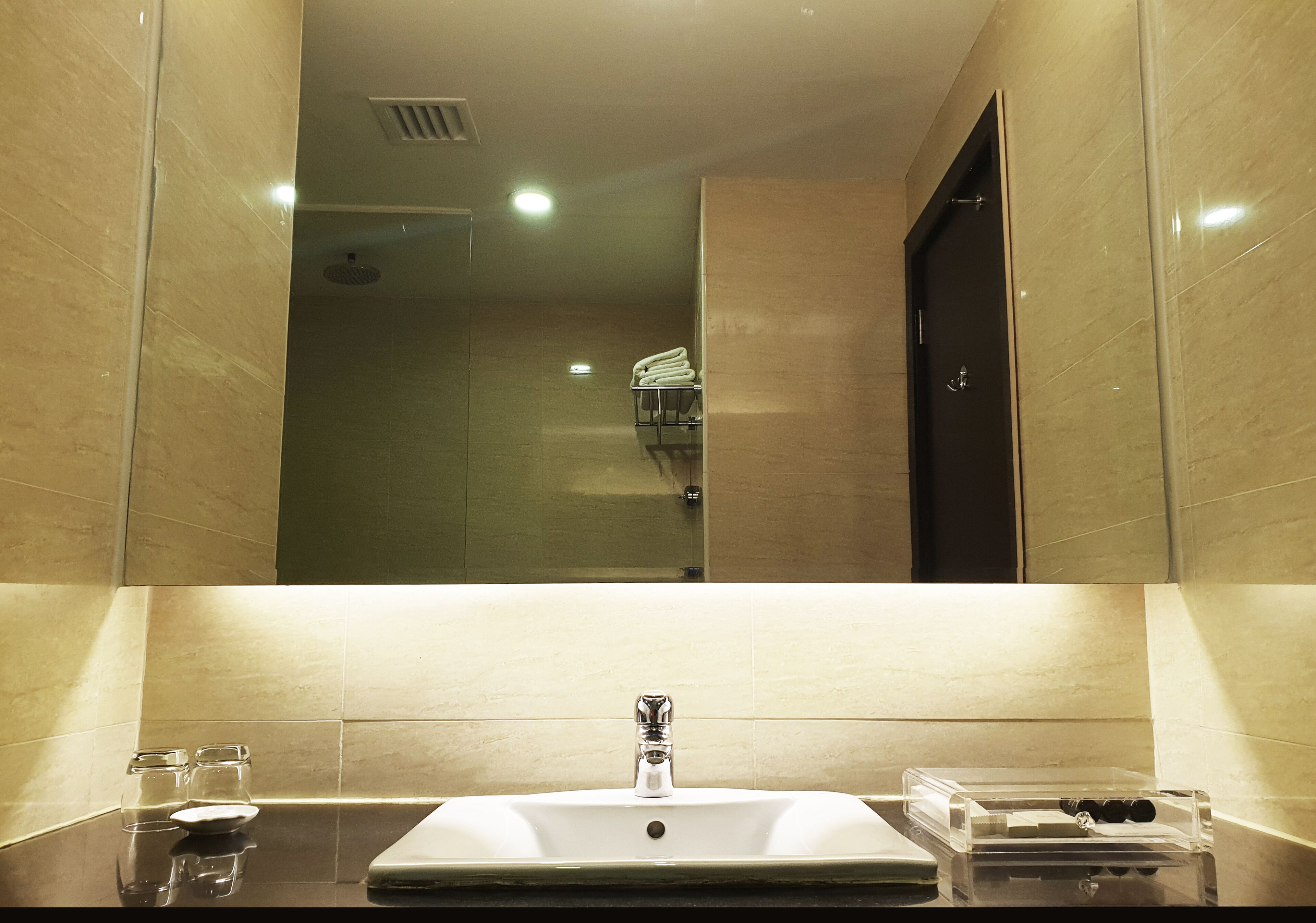 A bathroom with a large mirror, a sink, and a glass shower enclosure.