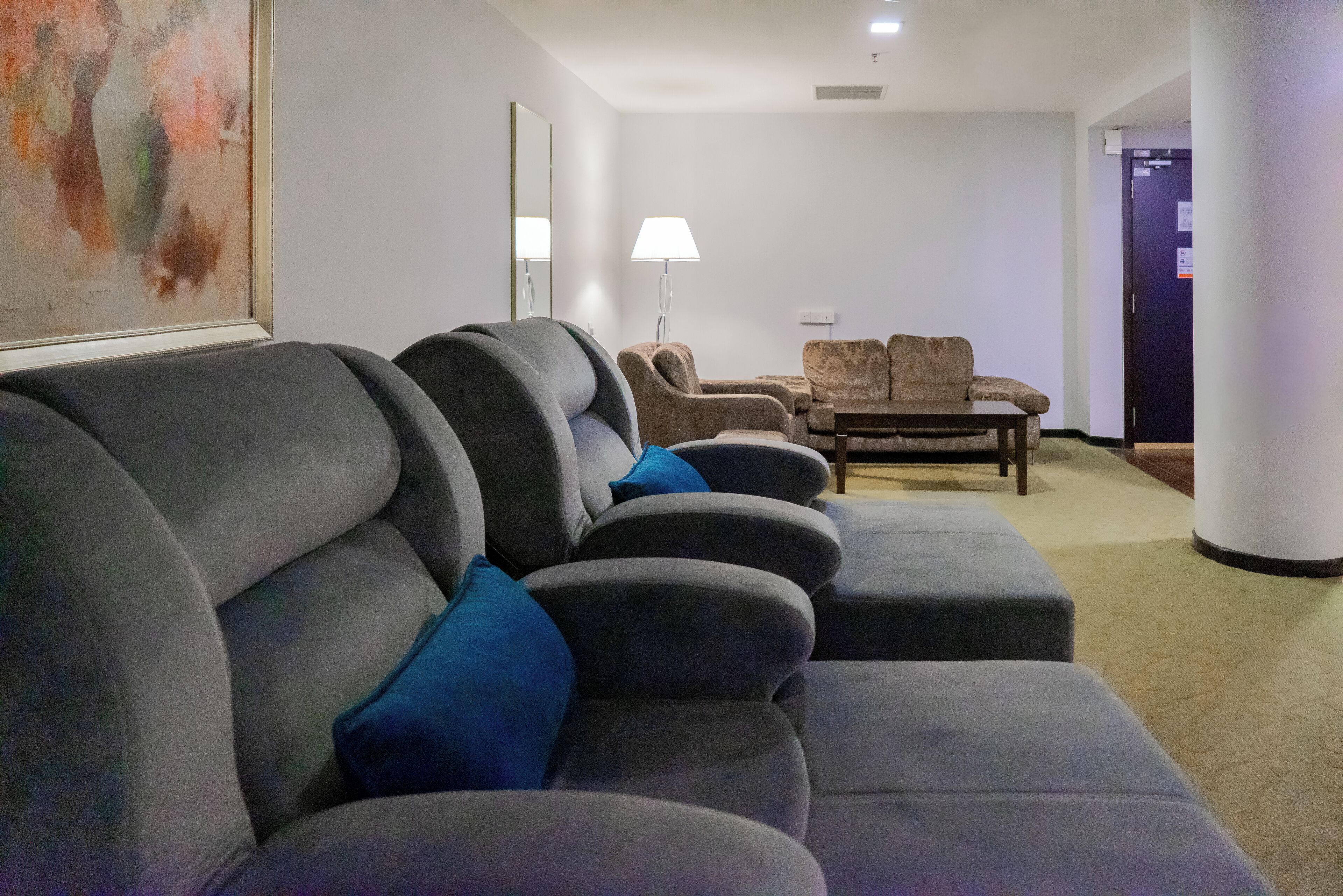 Una sala de estar moderna con un sofá seccional gris, una mesita de centro y una lámpara.