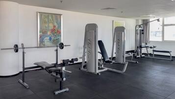 A gym with weightlifting equipment, benches, and a painting on the wall.