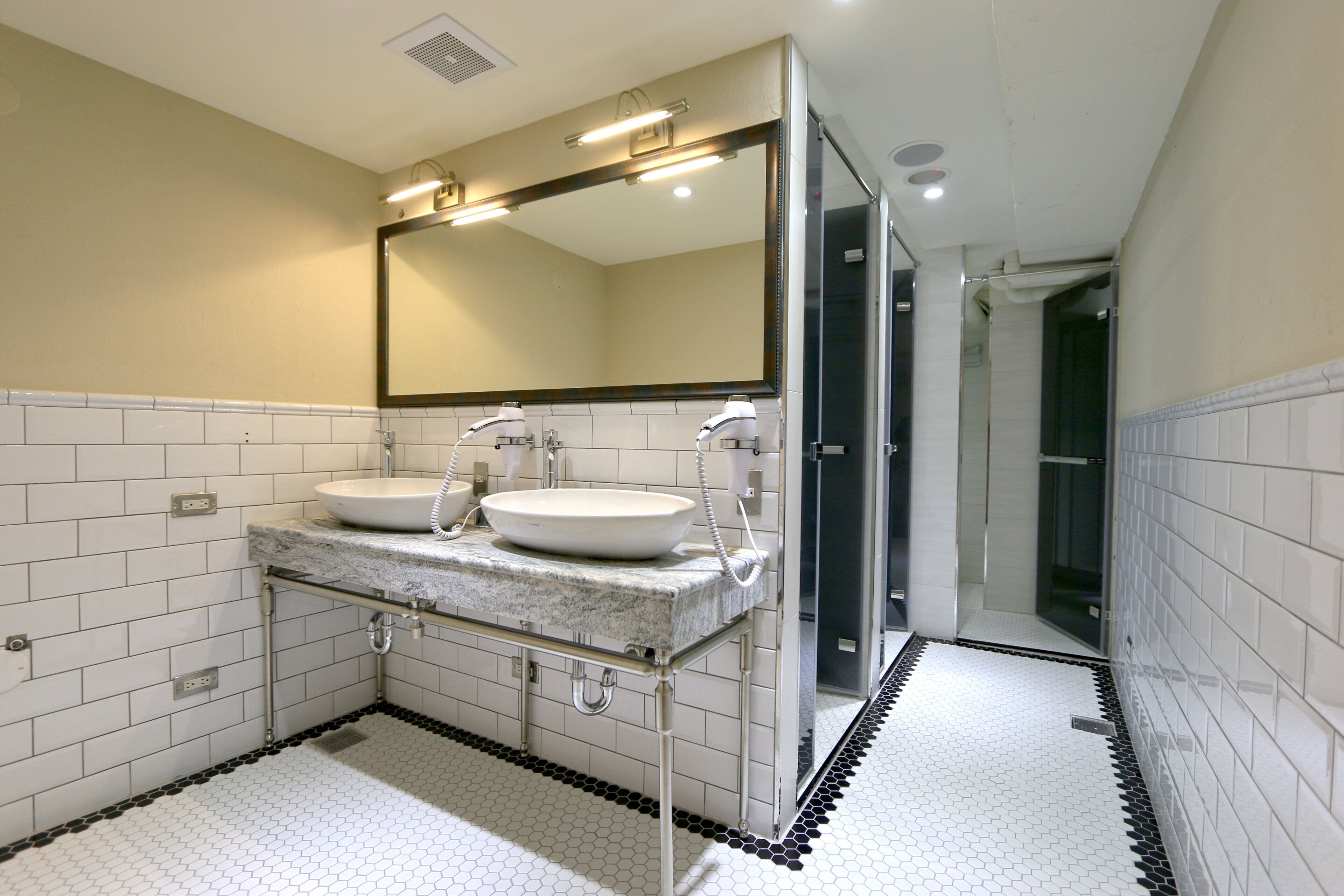 A modern bathroom with two sinks, a large mirror, and a shower area.