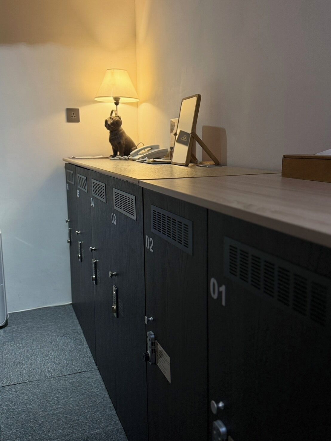 A storage locker with a lamp, a phone, and a picture frame on top.