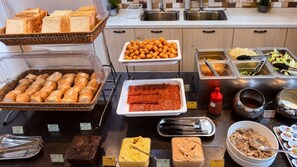 A buffet with various food items including bread, tater tots, and different sauces. - NK Hostel (Taipei)