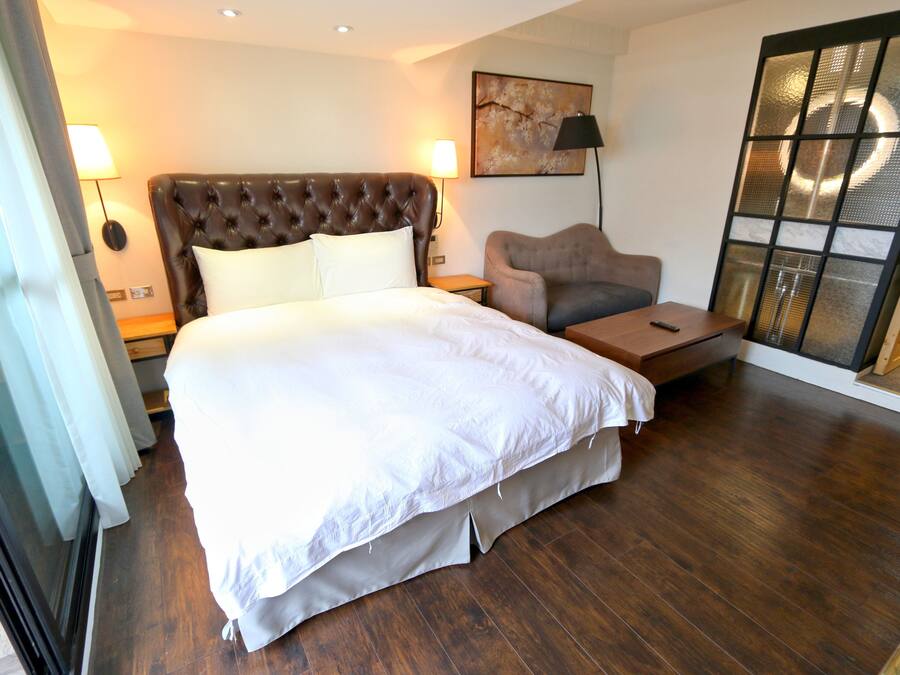 Habitación de hotel con una cama grande, un sofá, una mesita y un ventanal corredero.