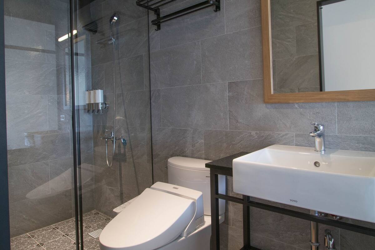 A modern bathroom with a glass-enclosed shower, a white toilet, and a vanity with a mirror.