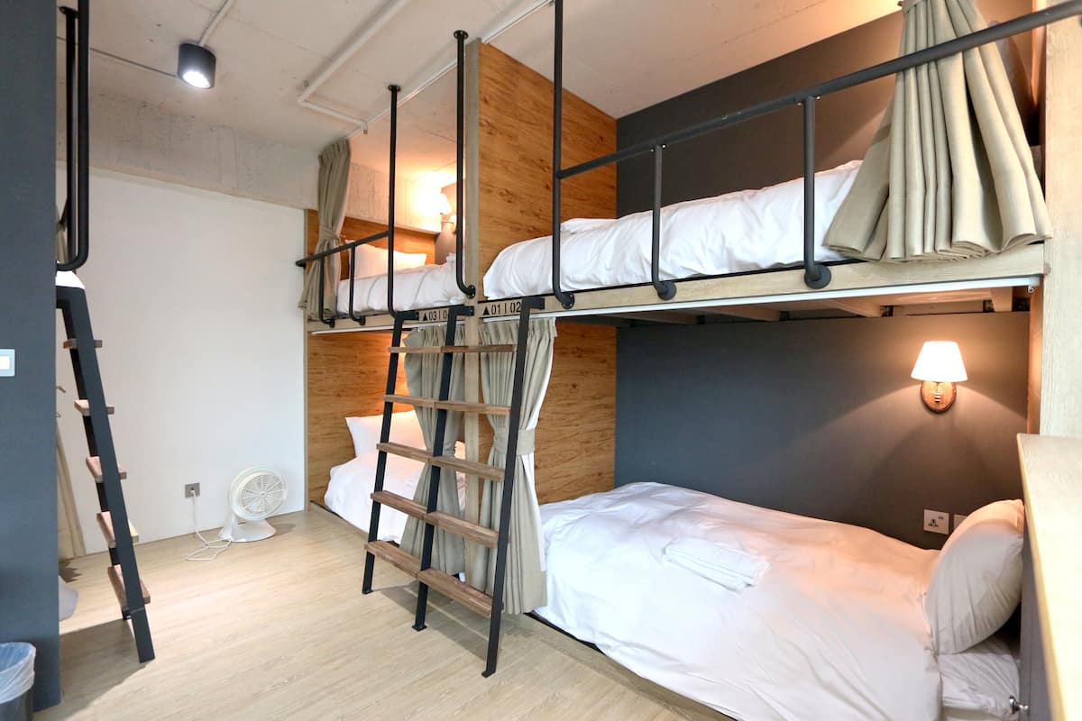 A bunk bed room with a ladder, a fan, and a wall-mounted lamp.