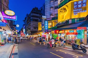 Une rue animée, avec de nombreux commerces et enseignes, témoignant d’une vie urbaine effervescente.