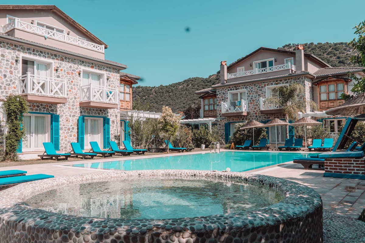 A pool area with lounge chairs and a hot tub, surrounded by stone buildings with balconies.