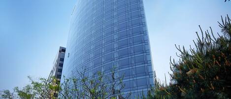 Un moderno edificio de gran altura con fachada de vidrio y el nombre "SHILTON STAY" visible en el costado.