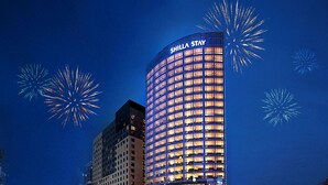 Un hotel moderno de gran altura, con fachada de vidrio y el nombre "SHILLA STAY" iluminado en la parte superior.