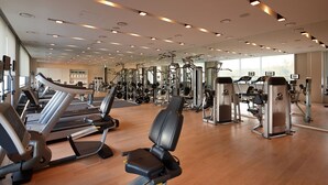Un gimnasio con cintas de correr, máquinas de pesas y pesas sueltas.