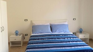 A bedroom with a bed, two bedside tables, and an air conditioning unit. - Case Corona (Santa Flavia)