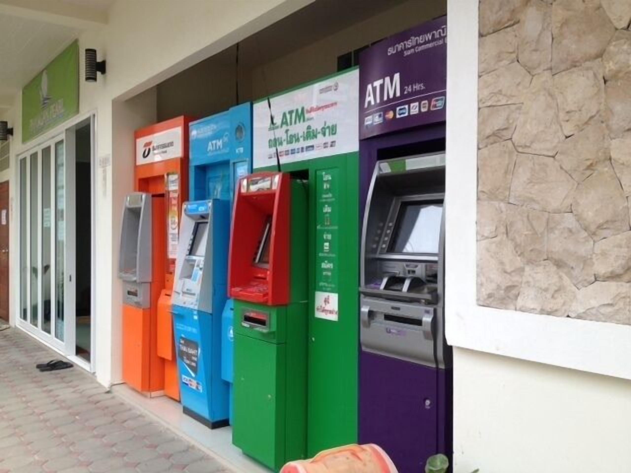 A row of ATMs in various colors outside a building.