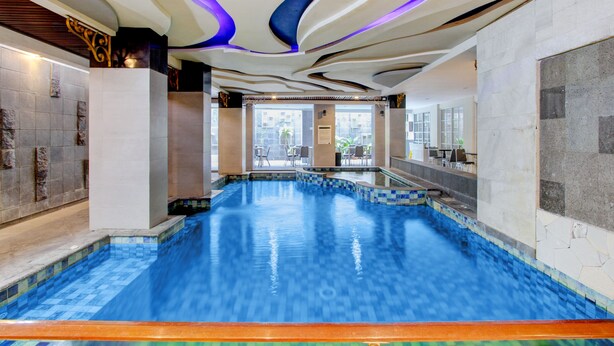 A swimming pool with a wavy ceiling design and a view of the outside. - Palette Grand Sae Boutique Hotel (Surakarta)