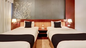 A hotel room with two beds, a nightstand with a phone, and a decorative wall piece. - Palette Grand Sae Boutique Hotel (Surakarta)