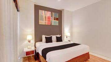 A hotel room with a bed, bedside lamps, a telephone, and a painting on the wall.