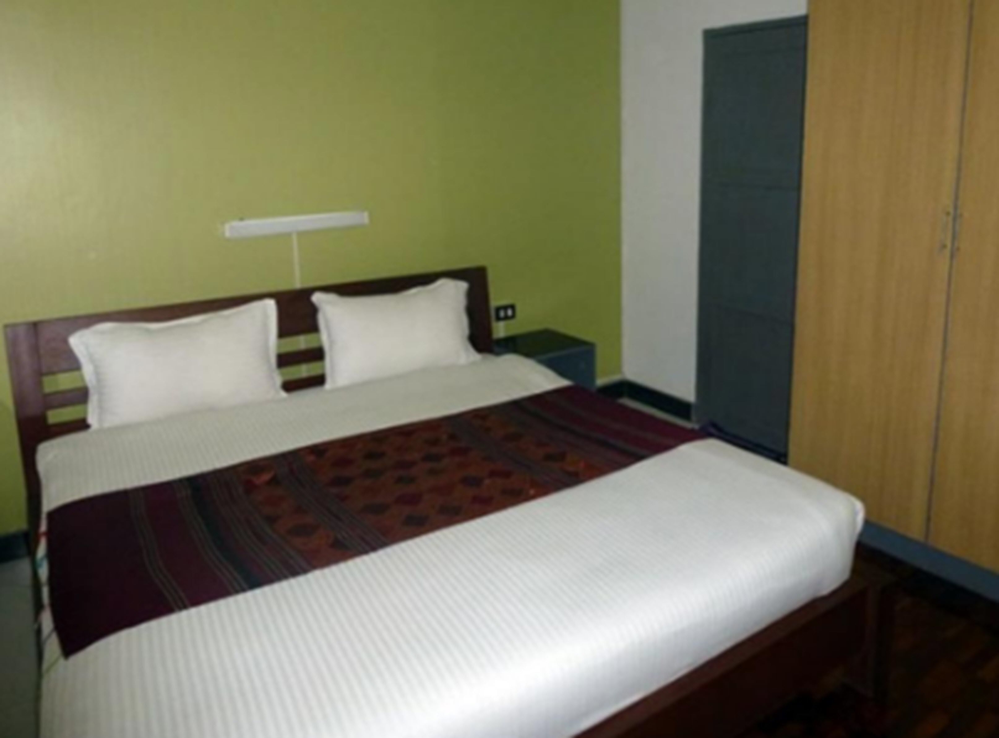A bed with a wooden headboard, two pillows, and a patterned bedspread.
