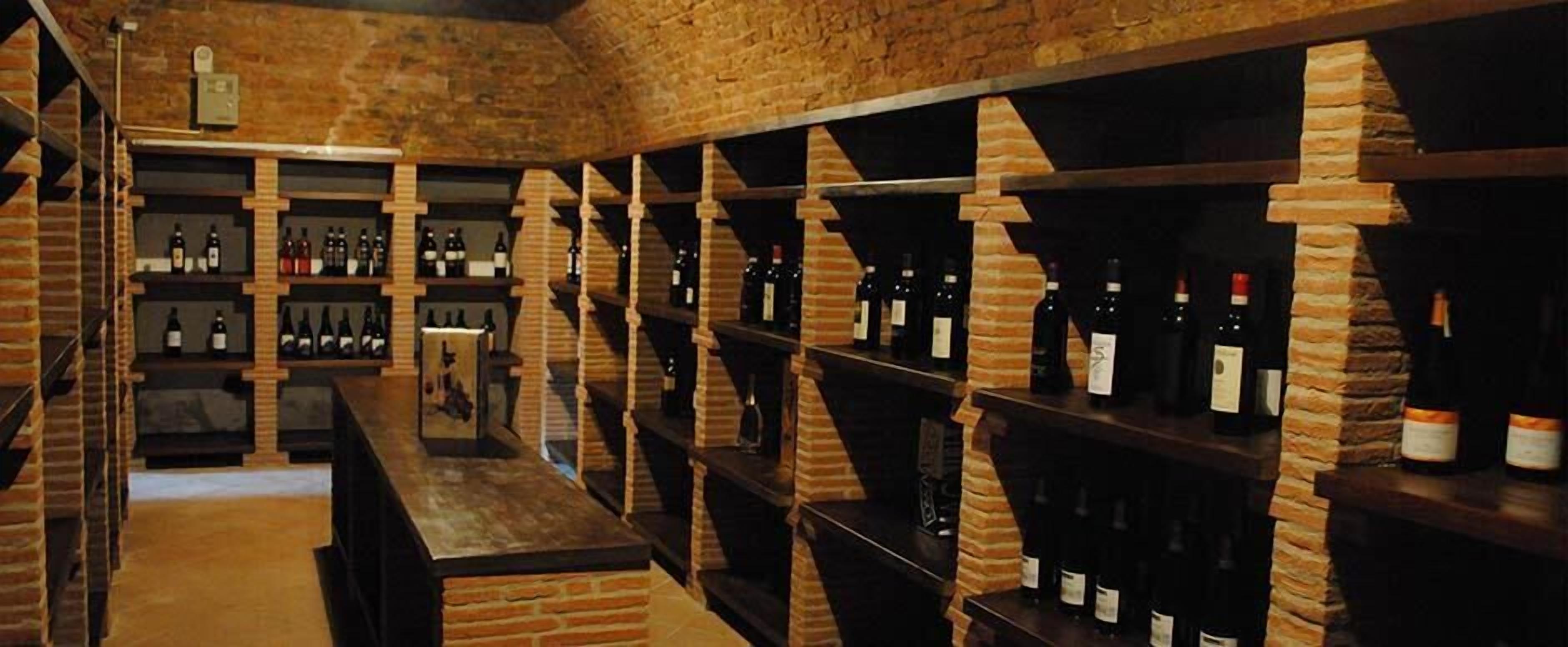 A wine cellar with brick walls and wooden shelves holding wine bottles.