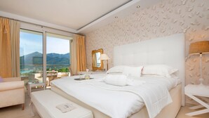 Habitación de hotel con una cama grande, un banco, un escritorio y vistas a las montañas.