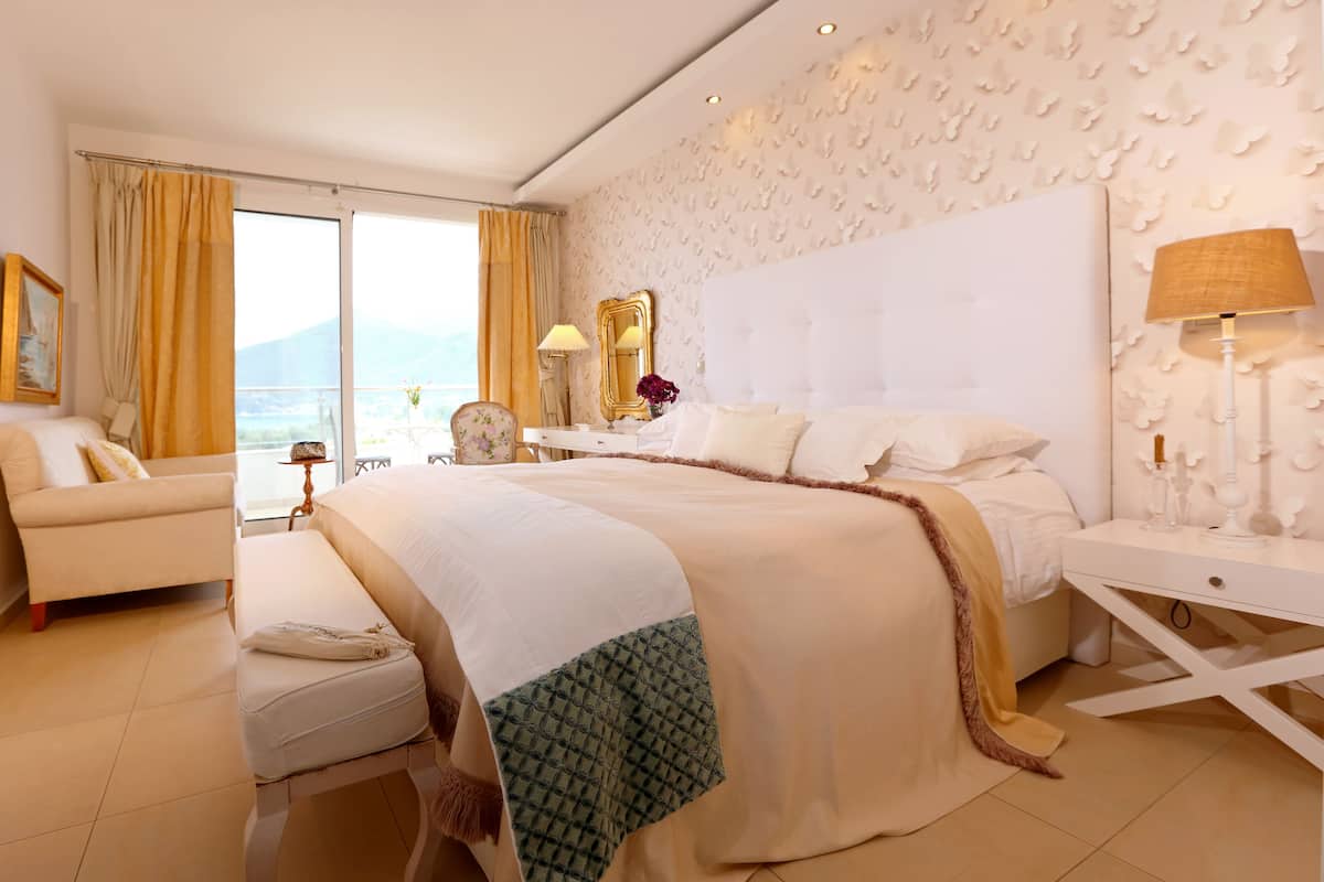A spacious bedroom with a large bed, a sitting area, and a view of the outdoors.
