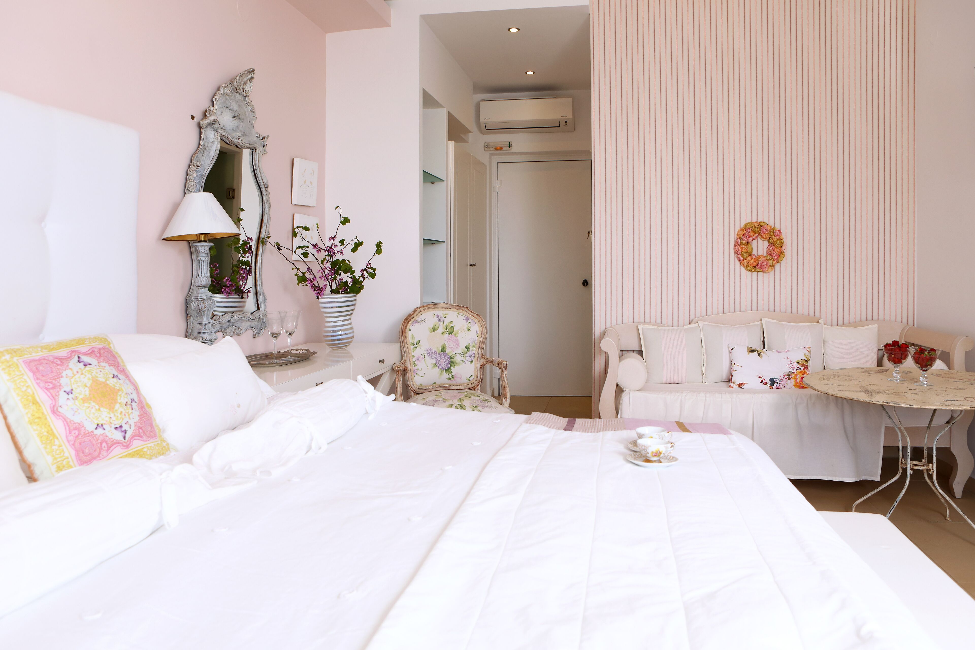 Ein Hotelzimmer mit einem großen Bett, einem kleinen Tisch mit Blumen, einem Sessel und einem Sofa.