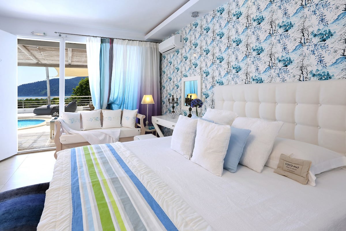 A hotel room with a large bed, a desk, and a view of a pool and mountains.