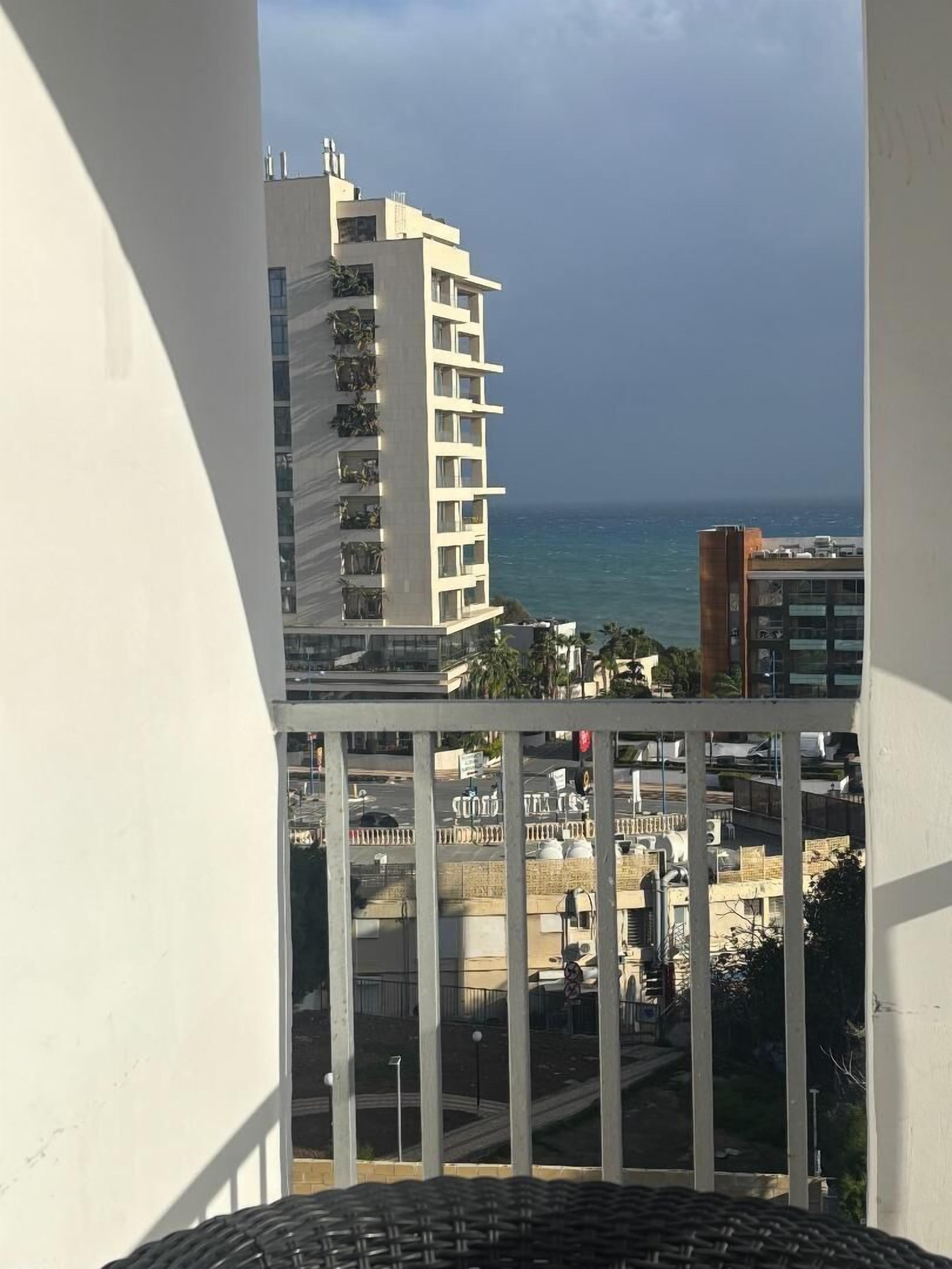 Un balcon avec vue sur un immeuble de grande hauteur et sur l’océan.