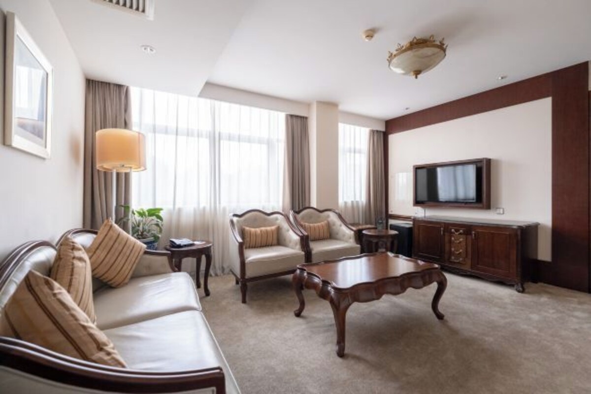 Una habitación de hotel con un sofá, una mesa de centro, un televisor y un armario.
