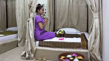 A room with a bed, a small table with toiletries, and a decorative bowl with flowers.