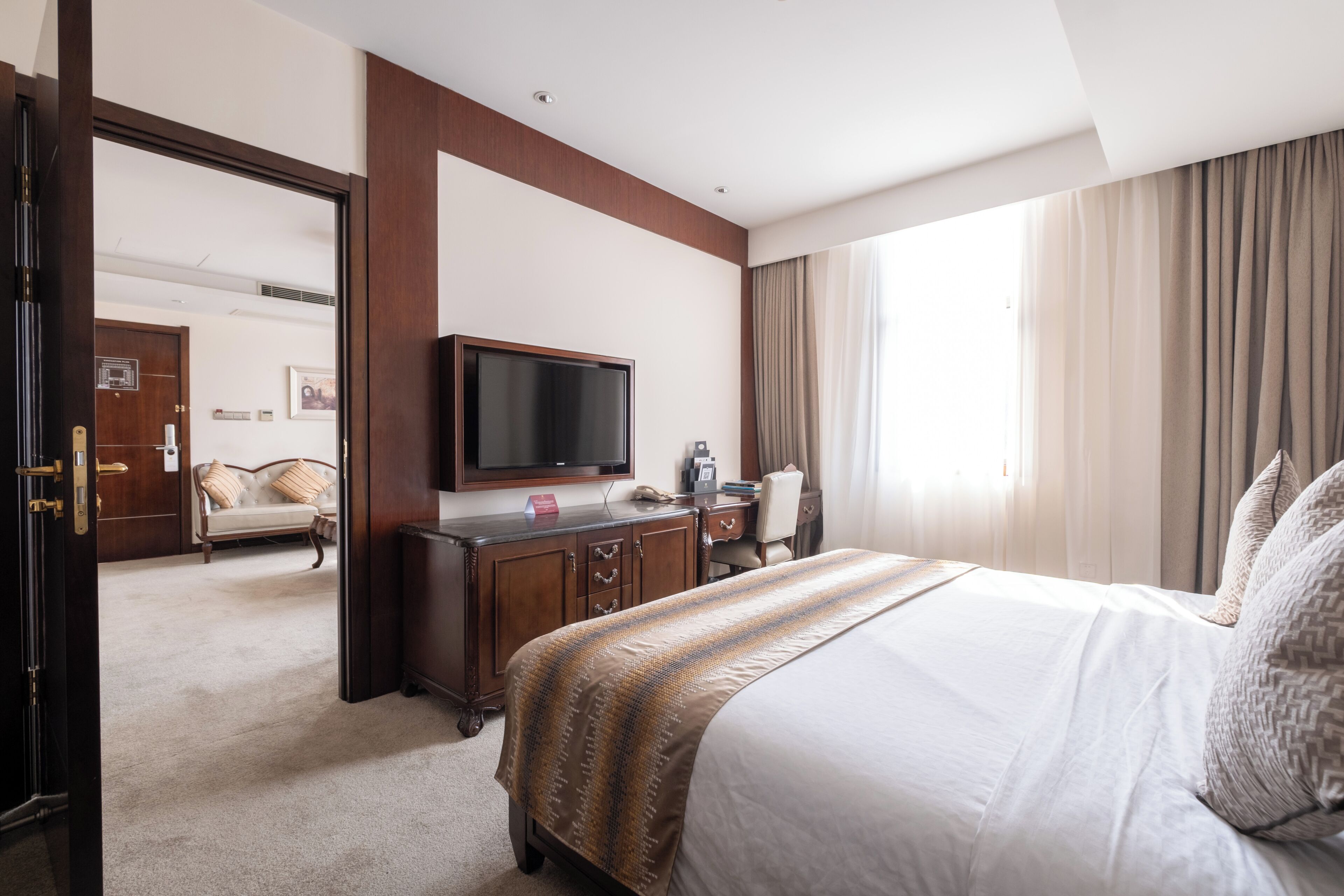 A hotel room with a large bed, a television, a desk, and a chair.