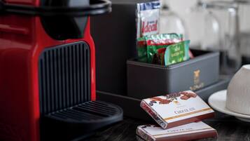 Une cuisine avec une machine à café rouge, une boîte de chocolats et un paquet de café.