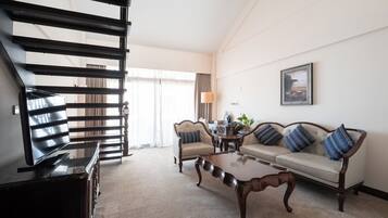 Una sala de estar con sofá, sillón, mesa de centro y televisor sobre un mueble.
