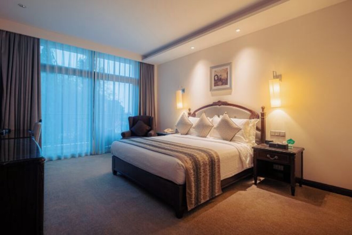 Habitación de hotel con una cama grande, lámparas de noche, un escritorio y una silla.