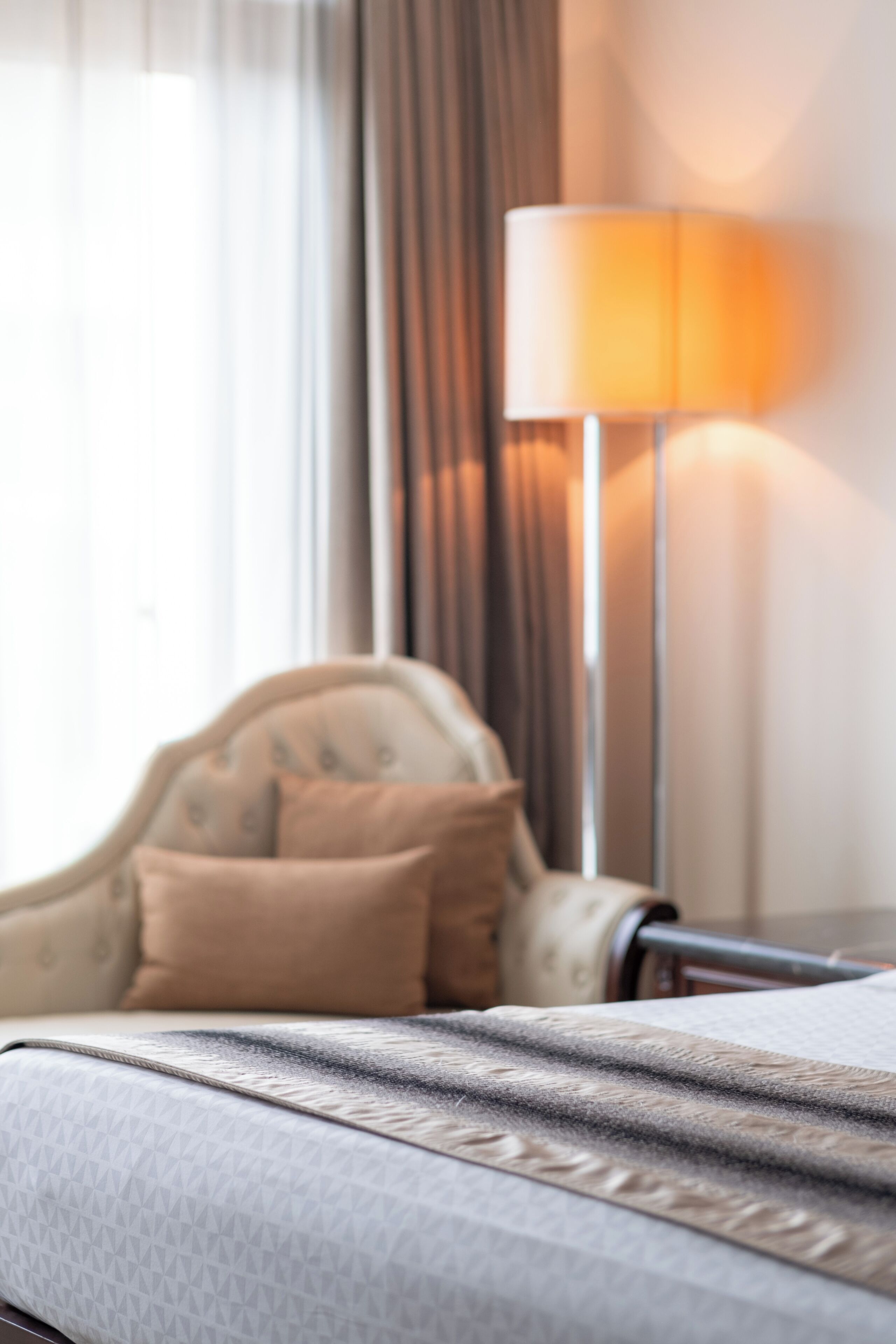 Una habitación de hotel con cama, lámpara y ventana con cortinas.