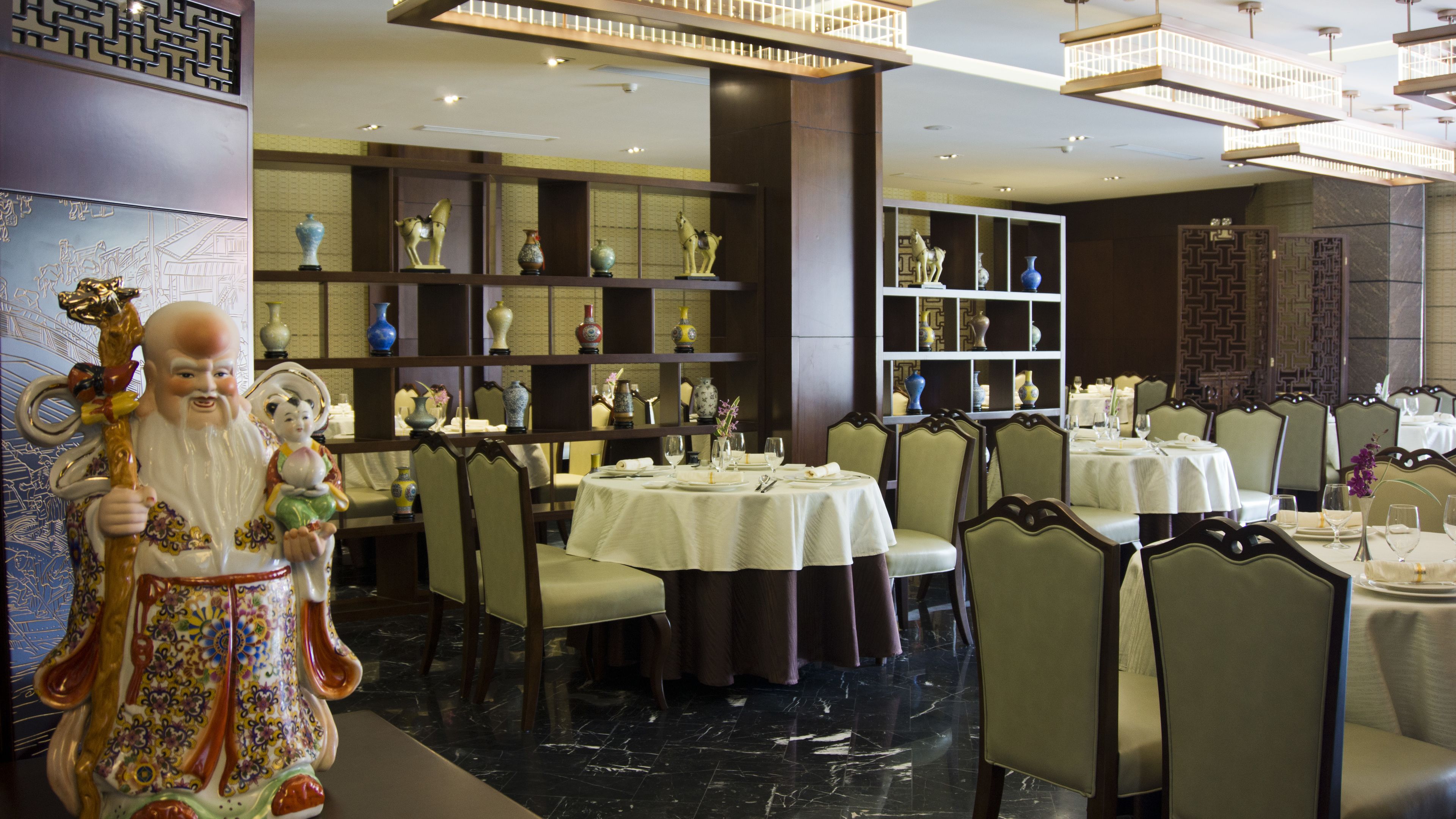 A restaurant with round tables, chairs, and decorative vases.
