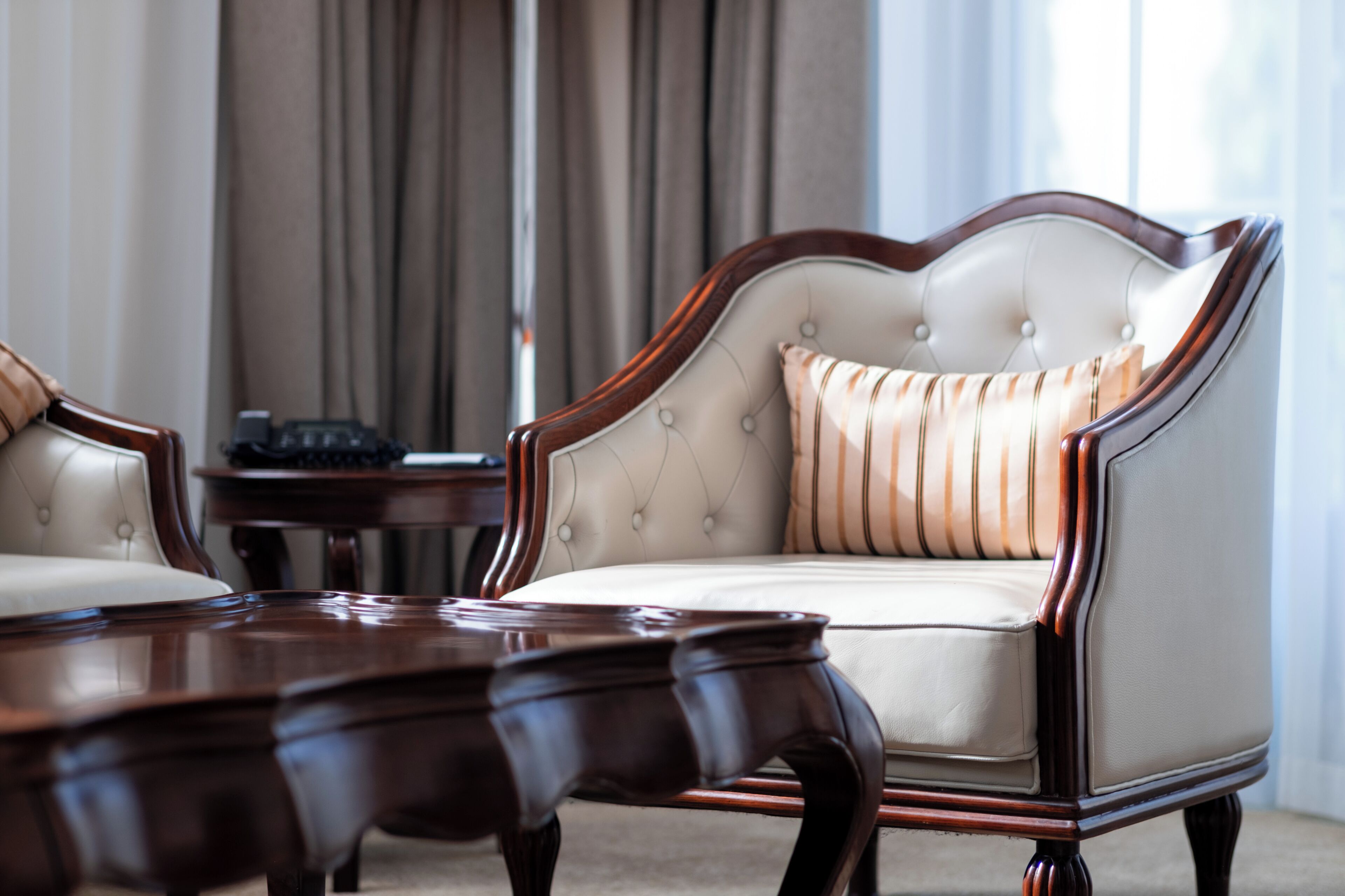 A room with a tufted sofa, a wooden coffee table, and a small side table.