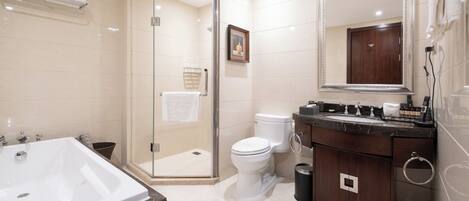 A bathroom with a glass-enclosed shower, a large bathtub, a toilet, and a vanity with a mirror.