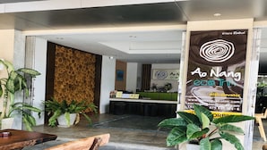 Ein Empfangsbereich mit einem Holzbüro, Topfpflanzen und einem großen Plakat, das ein Kaffeehaus bewirbt.