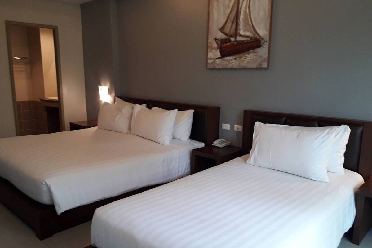 Habitación de hotel con dos camas, una mesita de noche con teléfono y un cuadro en la pared.